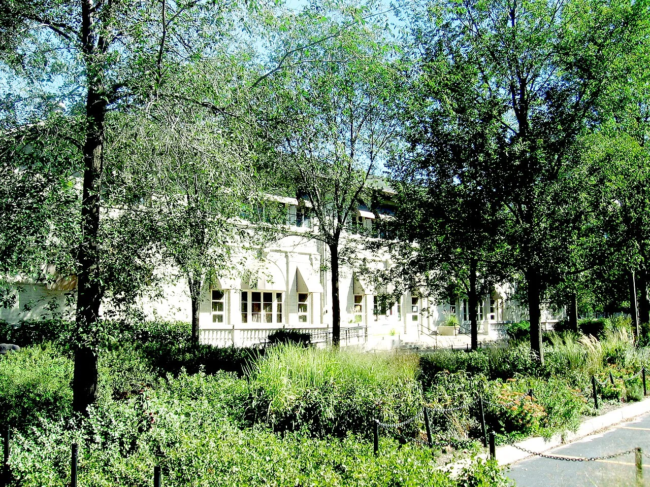 Hamilton Park Fieldhouse framed by leafy trees and garden plantings in Englewood.