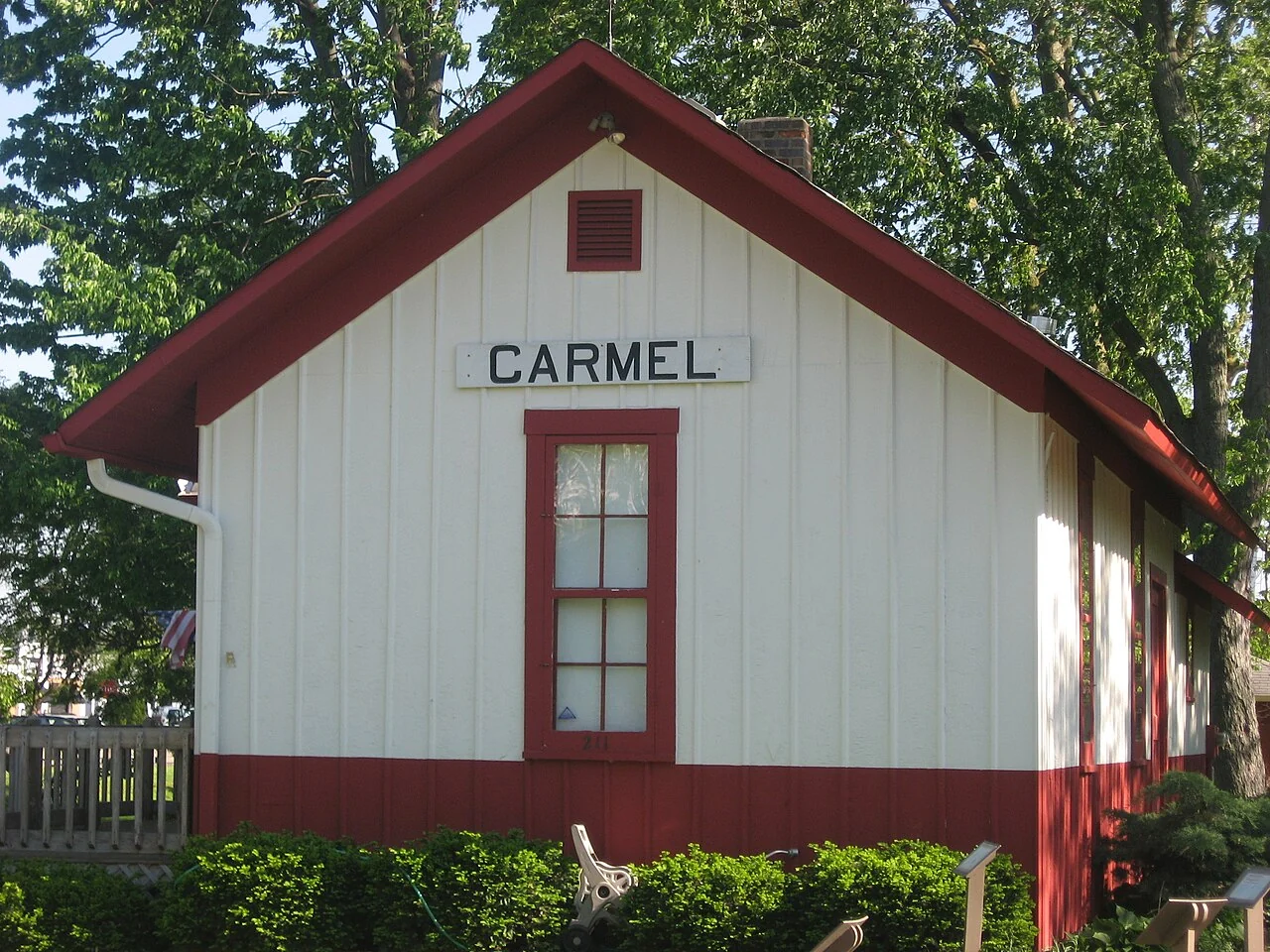 The historic Carmel Monon Depot with white siding, red trim, and its Carmel sign.