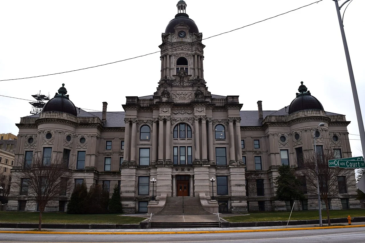 The ornate stone facade and central clock tower of the Old Vanderburgh County Courthouse.