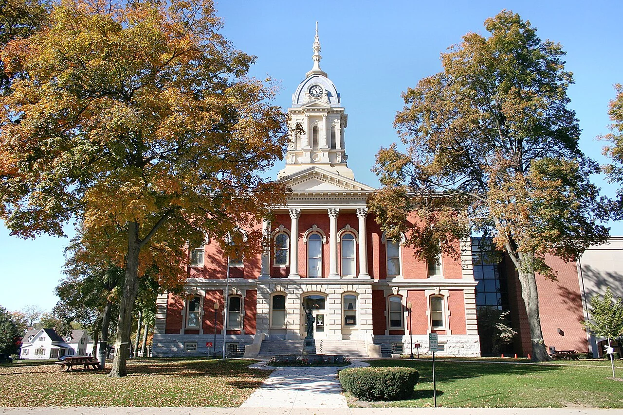 Marshall County Courthouse’s red brick facade and clock tower framed by autumn trees.