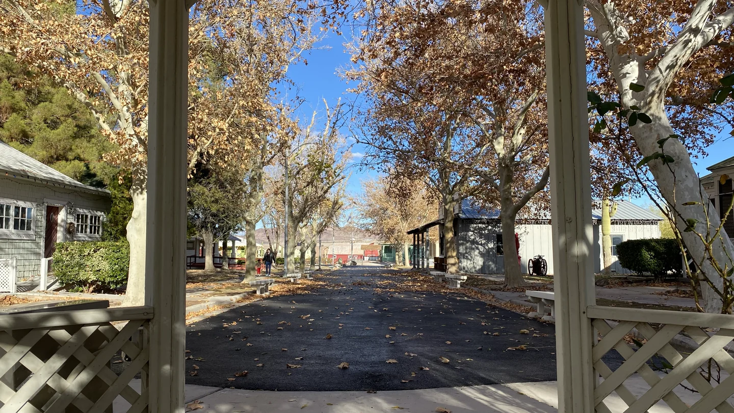 A tree-lined walkway among historic buildings at Clark County Museum in Henderson