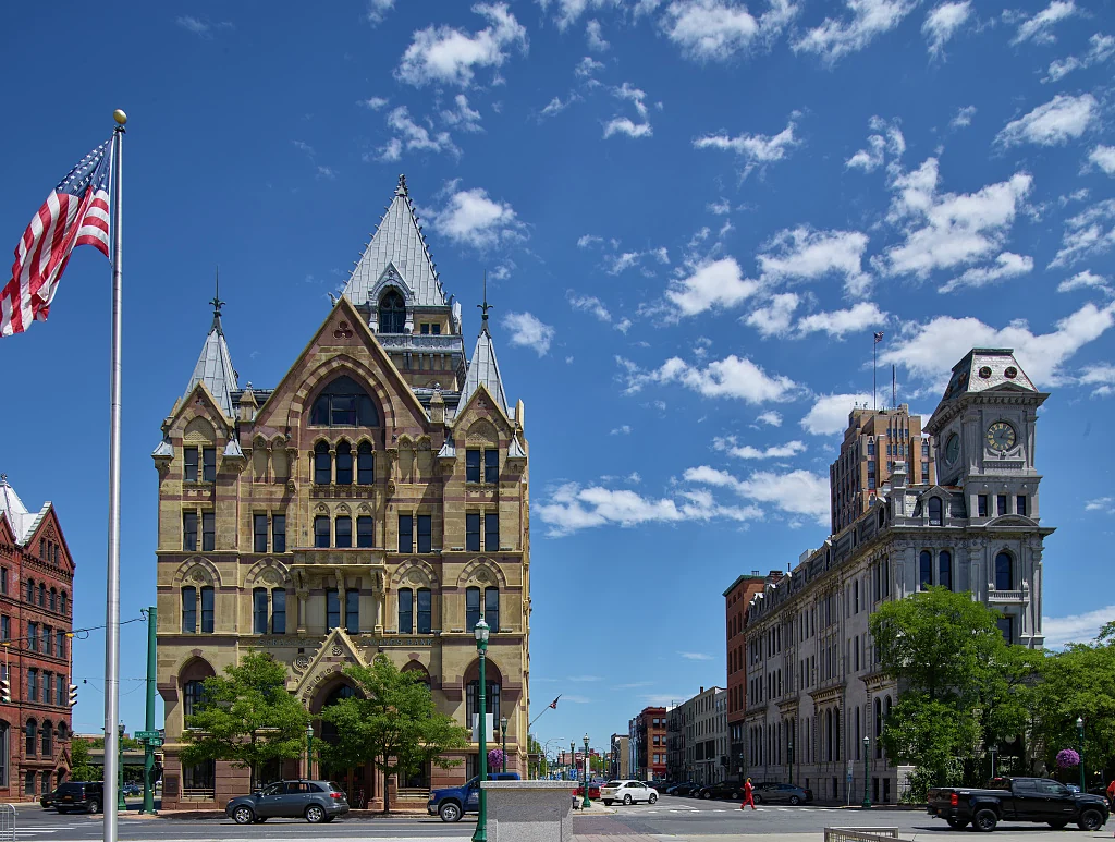 The ornate Syracuse Savings Bank and Gridley buildings beneath a blue sky on Clinton Square.