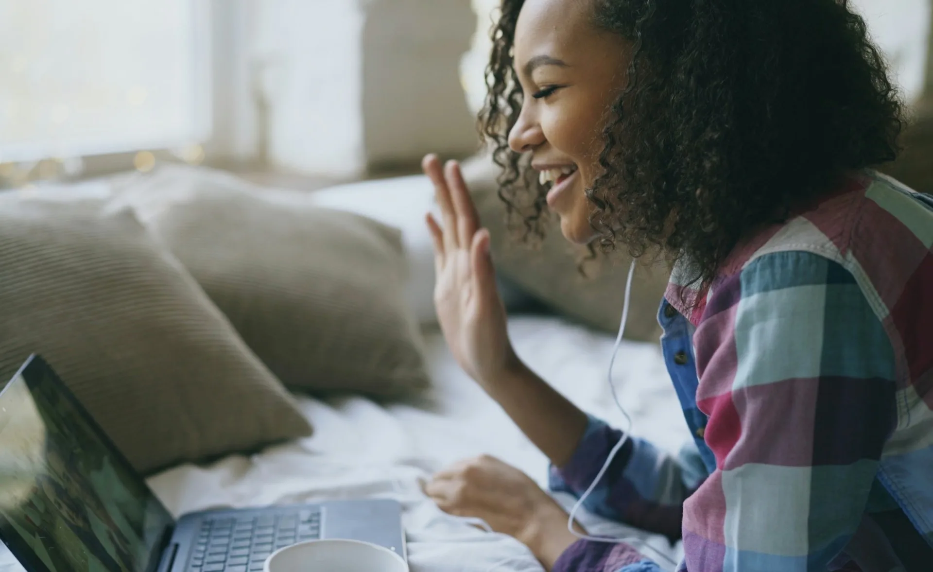 A patient smiling and waving during a video visit from home